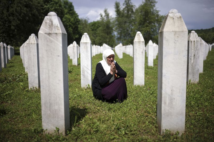 Mejra Djogaz mourns next to the graves of her two sons, victims of the Srebrenica genocide, at the Memorial Center in Potocari, Bosnia, Wednesday, May 22, 2024.