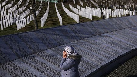 Bosnalı Müslüman bir kadın, Srebrenitsa Anma Merkezi'nde, Srebrenitsa soykırımında öldürülenlerin isimlerinin yazılı olduğu anıtın yanında dua ediyor