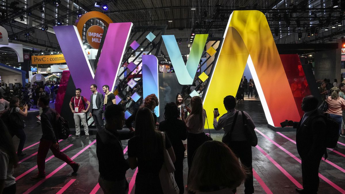 Show goers pose for photographs in front of the Vivatech logo at the Vivatech show in Paris, Thursday, June 15, 2023
