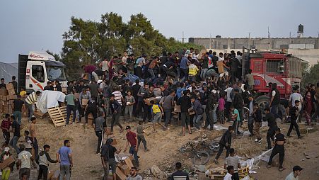 Palestinians are storming trucks loaded with humanitarian aid brought in through a new U.S.-built pier, in the central Gaza Strip, Saturday, May 18, 2024. 