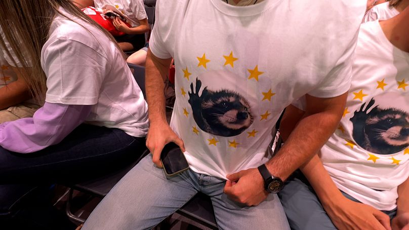 Un joven muestra una de las camisetas con el meme del mapache distribuidas por el PSOE