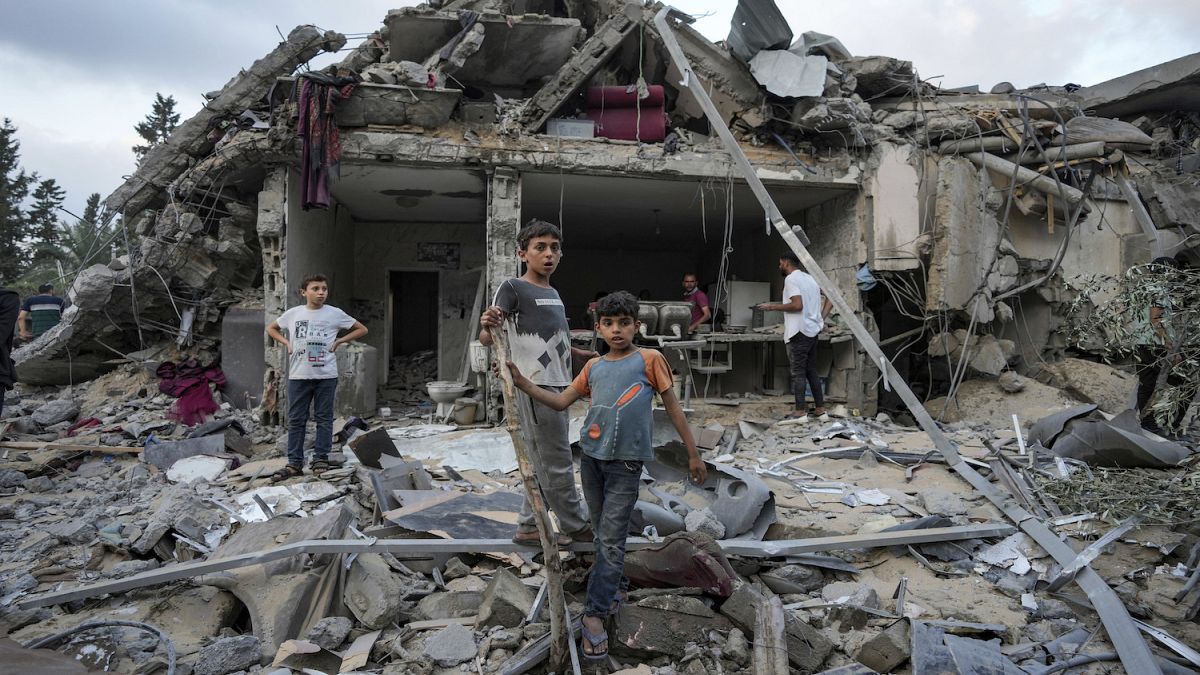 أطفال يقفون على أنقاض المنازل المدمرة في غزة