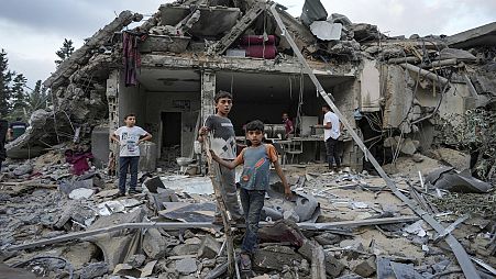 أطفال يقفون على أنقاض المنازل المدمرة في غزة