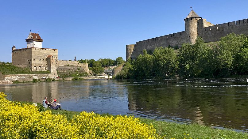 Men are seen fishing near the fortresses of Narva, left, and Ivangorod, Russia, right, in Narva, Estonia, on Wednesday, May 24, 2023.