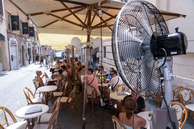 Customers enjoy the relief of a fan as they sit at a bar in downtown Rome.