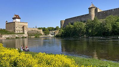 ARRCHIVES - Des hommes pêchent près des forteresses de Narva, à gauche, en Estonie, et d'Ivangorod, à droite, en Russie, le mercredi 24 mai 2023. 