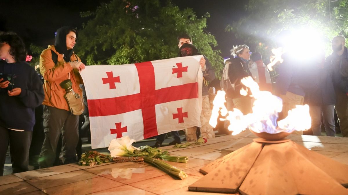 Demonstranten mit einer georgischen Flagge vor einer ewigen Flamme auf dem Heldenplatz in Tfilis, 14. Mai 2024