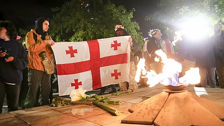Demonstranten mit einer georgischen Flagge vor einer ewigen Flamme auf dem Heldenplatz in Tfilis, 14. Mai 2024