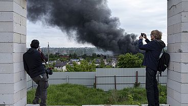 Giornalisti stranieri riferiscono da un punto di osservazione mentre si alza del fumo dopo un attacco russo a Kharkiv, Ucraina, venerdì 17 maggio 2024.