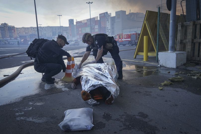 Des policiers couvrent un cadavre après que deux bombes guidées ont frappé un grand magasin de matériaux de construction à Kharkiv, en Ukraine, le samedi 25 mai 2024.