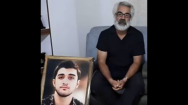 ماشالله کرمی در کنار عکس پسرش محمدمهدی کرمی