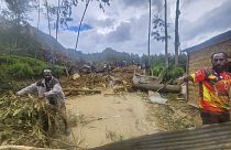 Villagers search through a landslide in Yambali 
