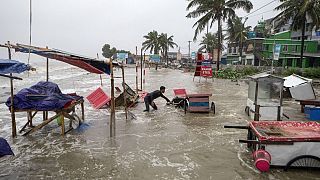 رجل يحاول انقاذ عربة ومواد أخرى بينما تتدفق المياه على شاطئ كواكاتا على ساحل خليج البنغال بسبب تقدم إعصار ريمال في باريسال، بنغلاديش، 26 مايو 2024.