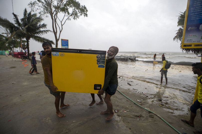 أشخاص يحاولون انقاذ ثلاجة بينما تتدفق المياه إلى شاطئ كواكاتا على ساحل خليج البنغال بسبب تقدم إعصار ريمال في باريسال، بنغلاديش، 26 مايو 2024