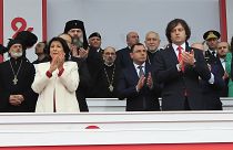  A Presidente Salome Zourabichvili, à esquerda, e o Primeiro-Ministro Irakli Kobakhidze, à direita, participam numa celebração do Dia da Independência em Tbilissi, a 26 de maio de 2024