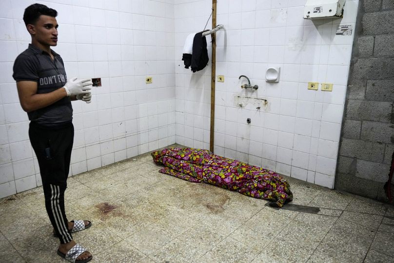A Palestinian medic stands near a body while he waits for others killed in the Israeli bombardment of the Gaza Strip at the morgue of Al Aqsa hospital on Sunday, May 26 2024.