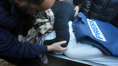 سيدة تحتضن جثمان الصحفي الفلسطيني أكرم الشافعي، الذي قُتل في القصف الإسرائيلي لقطاع غزة، في مشرحة مستشفى غزة الأوروبي في رفح، السبت، 6 يناير