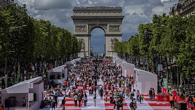 People eat their lunch as part of a giant picnic on the Champs-Elysées, in front of the Arc de Triomphe, organized by the Comité Champs-Élysées, Sunday, May 26, 2024 in Paris.