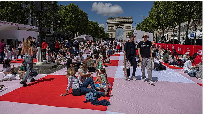 People eat their lunches as part of a giant picnic on the Champs-Elysées, in front of the Arc de Triomphe, organized by the Comité Champs-Élysées, Sunday, May 26, 2024 in Pari