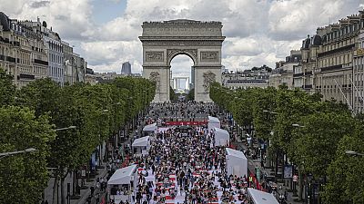 Des personnes déjeunent dans le cadre d'un pique-nique géant sur les Champs-Elysées, devant l'Arc de Triomphe, organisé par le Comité Champs-Élysées, dimanche 26 mai 2024