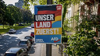 Ein AfD-Wahlplakat für die Europawahl mit der Aufschrift "Unser Land zuerst" wird am Montag, 13. Mai 2024, in Frankfurt am Main an einem Mast befestigt.