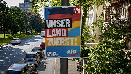 Ein AfD-Wahlplakat für die Europawahl mit der Aufschrift "Unser Land zuerst" wird am Montag, 13. Mai 2024, in Frankfurt am Main an einem Mast befestigt.