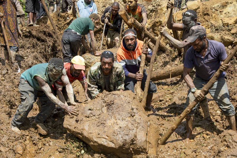 In this photo released by UNDP Papua New Guinea, villagers search through a landslide in Yambali village, in the Highlands of Papua New Guinea.