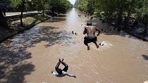  مجموعة من الشباب الباكستانيين يقفزون في الماء بينما يسبحون هم وآخرون في قناة لِتهدئة أنفسهم من حرارة الطقس في لاهور، باكستان، يوم الأحد 26 مايو 2024.