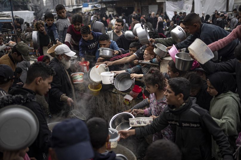 İnsani yardım kuruluşlarınca dağıtılan yemekten almaya çalışan Gazzeli siviller