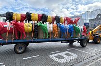 A tractor pulls a trailer filled with plastic cows prior to a protest of farmers outside of a meeting of EU agriculture ministers in Brussels.