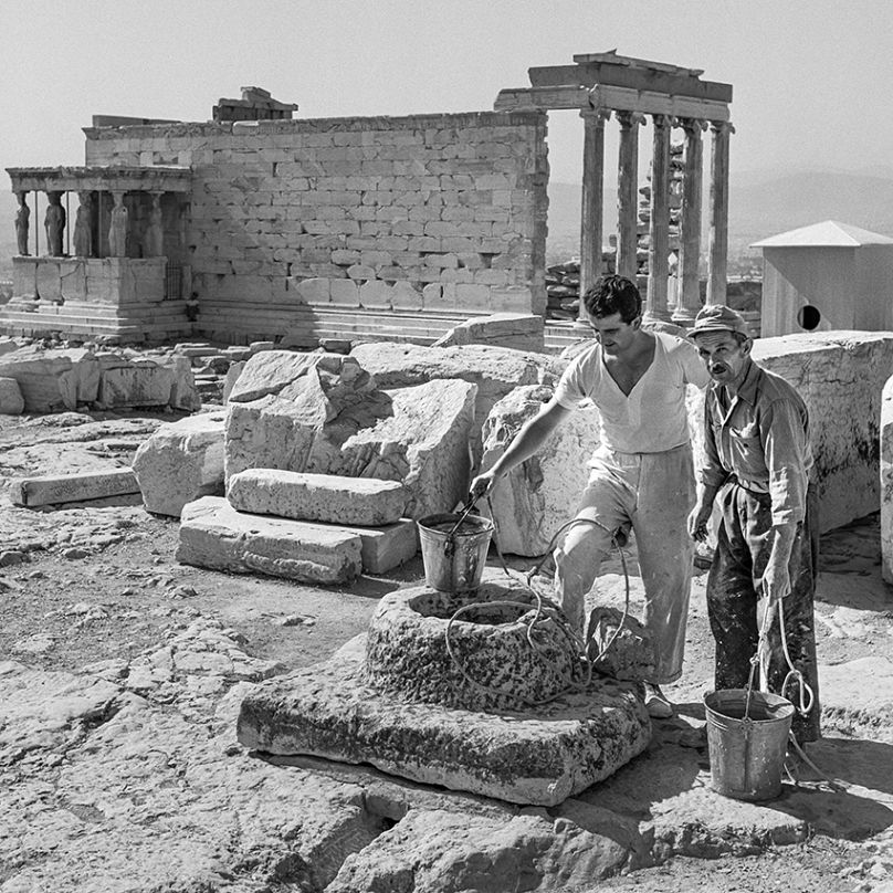 Εργάτες παίρνουν νερό με κουβά από την αρχαία δεξαμενή δίπλα στον Παρθενώνα.