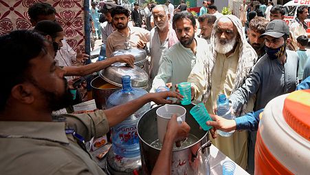 Volunteers provide lime sugar water to people at a camp set up to prevent heat stroke on a hot summer day, in Karachi.