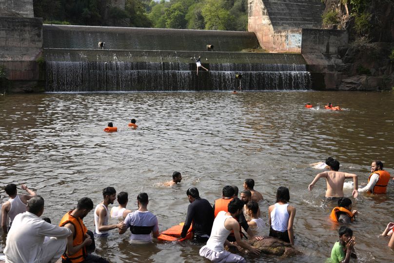 Pakistani youths cool themselves off in a stream during extreme heat. 
