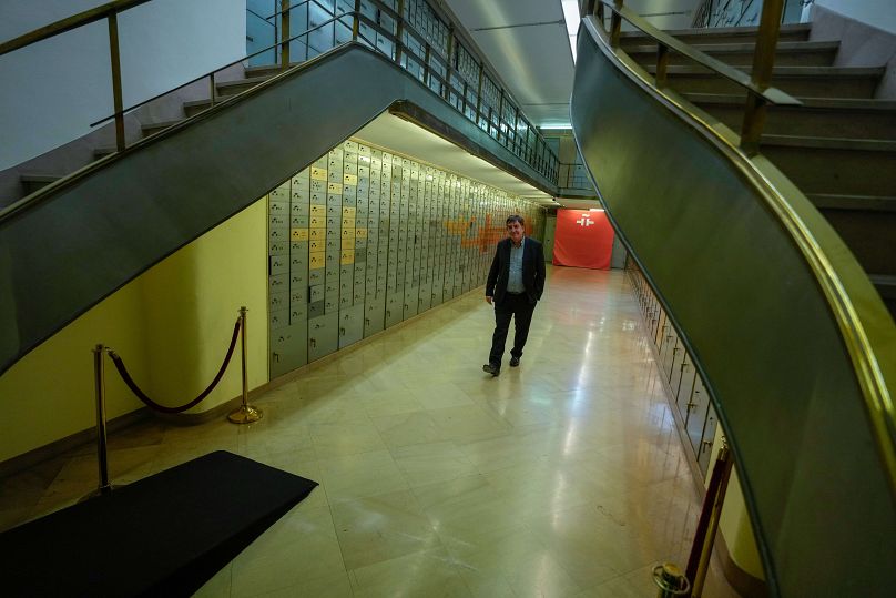 Luis Garcia Montero walks past safe boxes inside the old bank vault