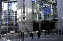 Pessoas caminham em frente ao Parlamento Europeu em Bruxelas