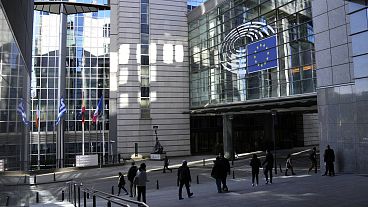 Pessoas caminham em frente ao Parlamento Europeu em Bruxelas