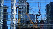 Cranes at a construction site in the Central Business District are reflected on a window panels of an office building in Beijing, Sunday, May 26, 2024. 