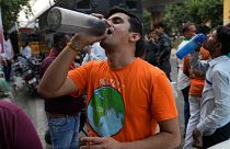 Um homem bebe água numa banca à beira da estrada que serve água potável gratuita aos passageiros, numa altura em que a vaga de calor continua a assolar a capital indiana, Nova Deli.
