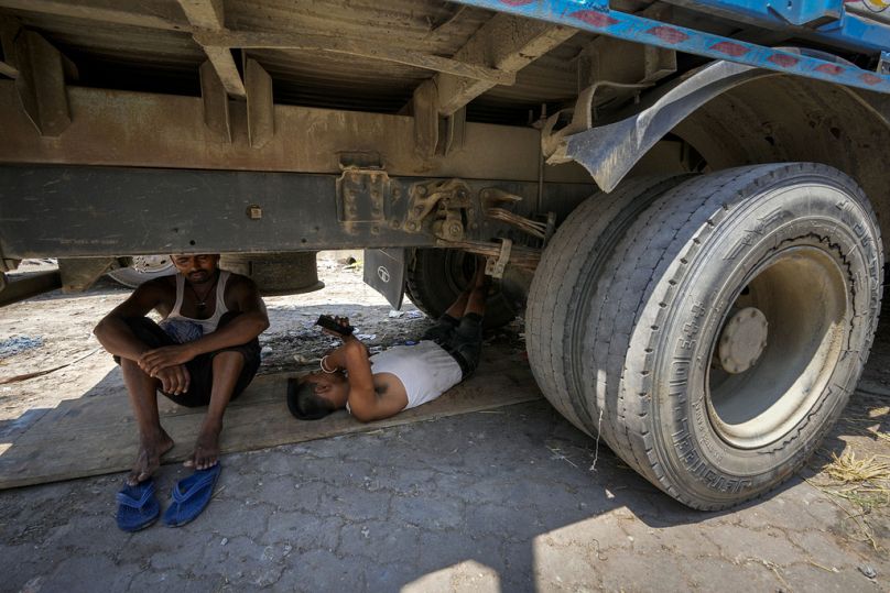 Workers take refuge beneath a parked truck from the scorching heat, in Guwahati, India.