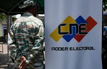 A Bolivarian Militia member stands guard next to a banner of the National Electoral Council where people can register to vote in Caracas, Venezuela.
