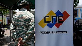 Un miembro de la Milicia Bolivariana monta guardia junto a una pancarta del Consejo Nacional Electoral en Caracas, Venezuela.