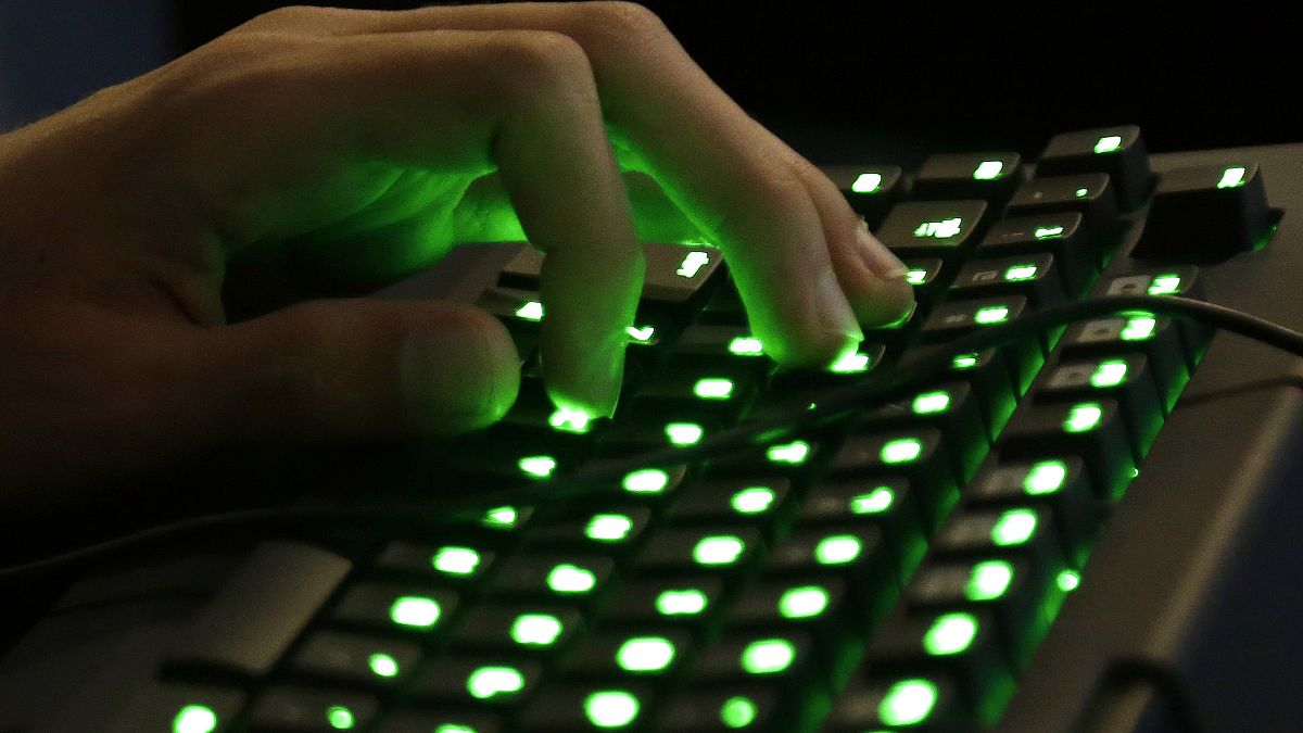 Die Hand einer Person ruht auf einer beleuchteten Tastatur.