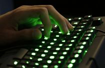A person's hand rests on an illuminated keyboard.