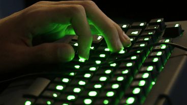 A person's hand rests on an illuminated keyboard.