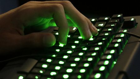 Die Hand einer Person ruht auf einer beleuchteten Tastatur.