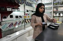 یک فروشنده تلفن همراه در مغازه‌اش در مرکز شهر تهران