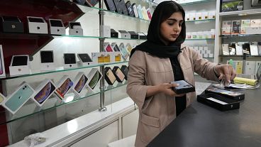 یک فروشنده تلفن همراه در مغازه‌اش در مرکز شهر تهران