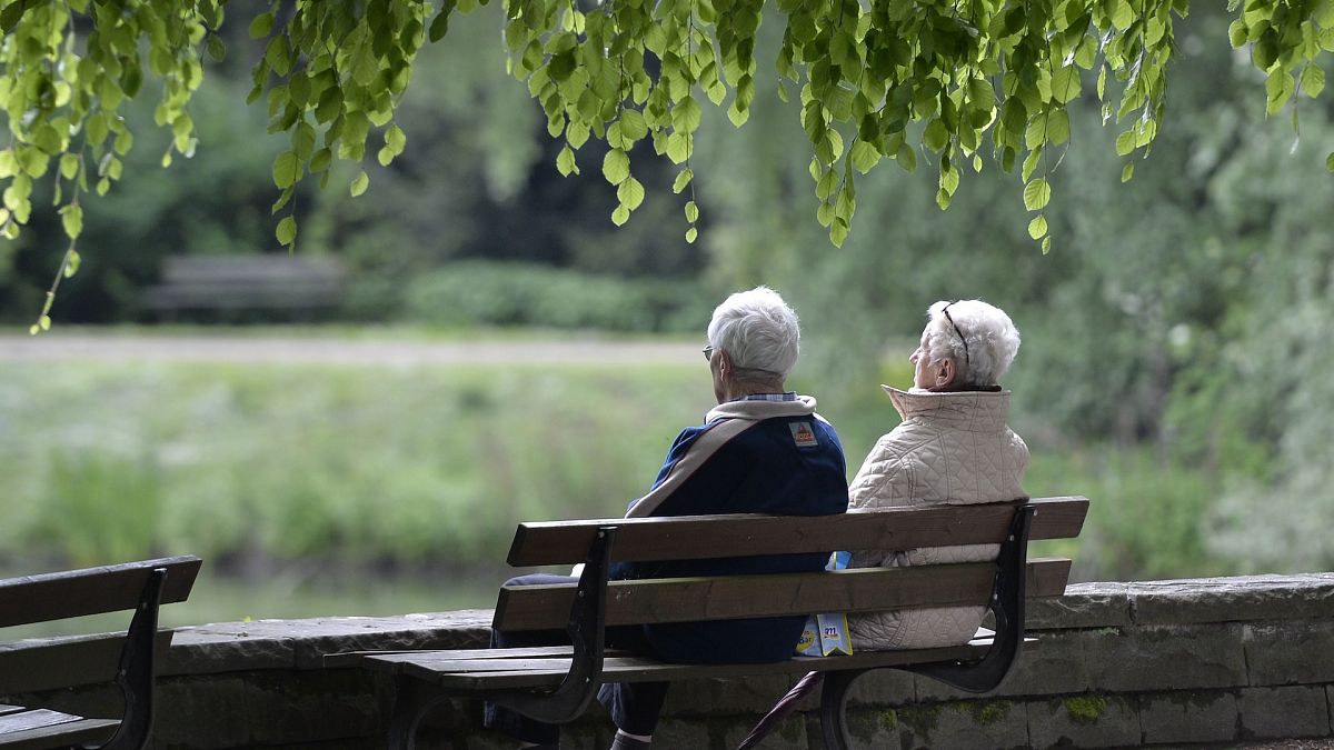 Um casal de idosos senta-se num banco de um parque em Gelsenkirchen, na Alemanha.