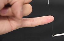 Close of fine bioelectronic silk sensor being wound around a forefinger then a little finger.