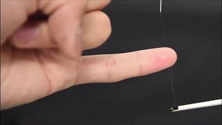 Close of fine bioelectronic silk sensor being wound around a forefinger then a little finger.